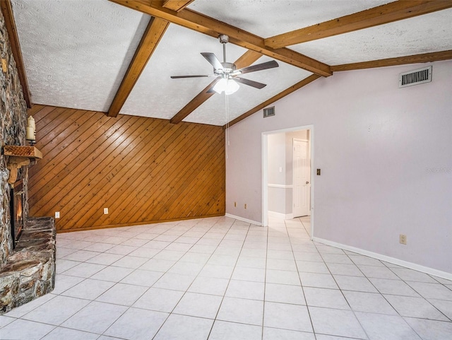 unfurnished living room featuring vaulted ceiling with beams, visible vents, wood walls, and a textured ceiling