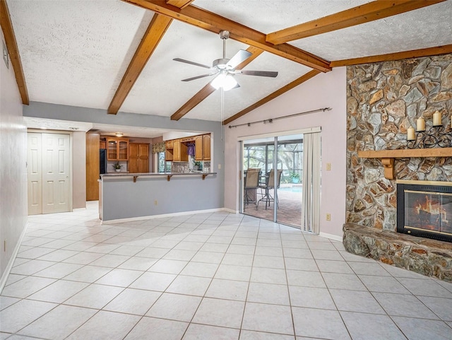 unfurnished living room with lofted ceiling with beams, light tile patterned floors, a stone fireplace, a textured ceiling, and a ceiling fan