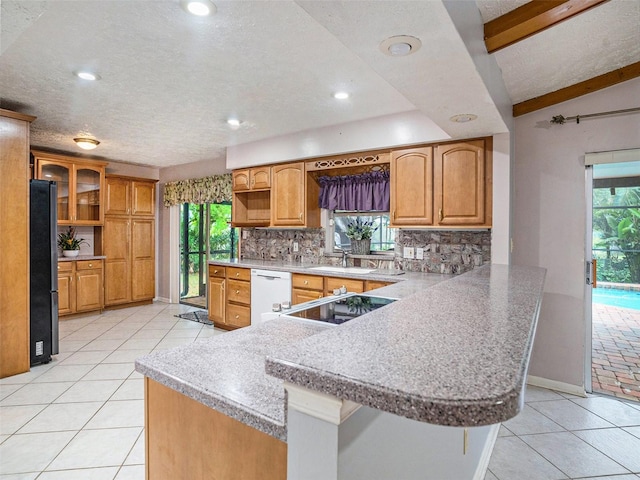 kitchen with a peninsula, freestanding refrigerator, a sink, dishwasher, and backsplash