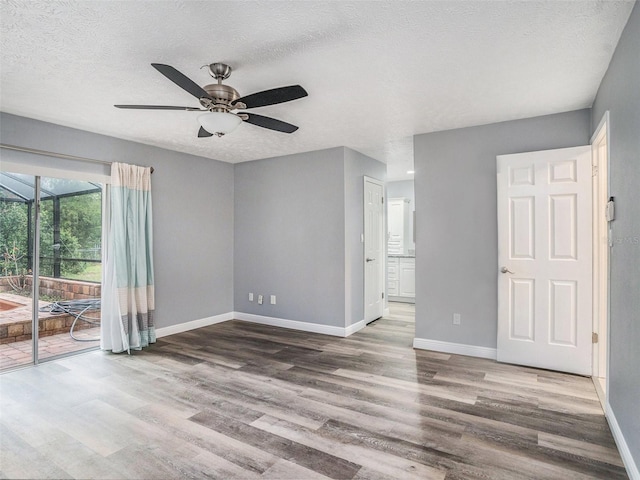 empty room with ceiling fan, wood finished floors, baseboards, and a textured ceiling