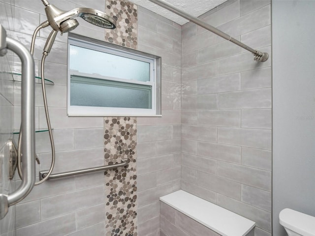 full bath with toilet and a tile shower