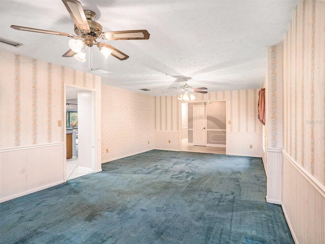 spare room featuring a wainscoted wall, visible vents, a textured ceiling, carpet, and wallpapered walls