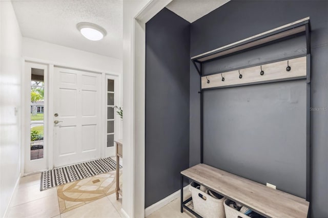 mudroom with tile patterned floors, a textured ceiling, and baseboards