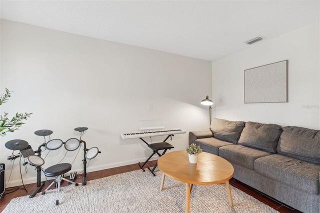 living room with wood finished floors, visible vents, and baseboards