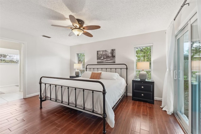 bedroom featuring a ceiling fan, wood finished floors, visible vents, and a textured ceiling