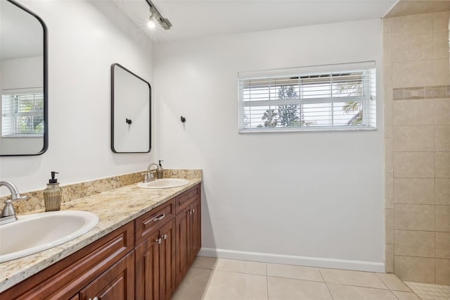 bathroom with tile patterned flooring, double vanity, baseboards, and a sink