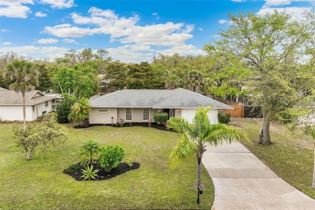 ranch-style home with a front lawn, an attached garage, and driveway