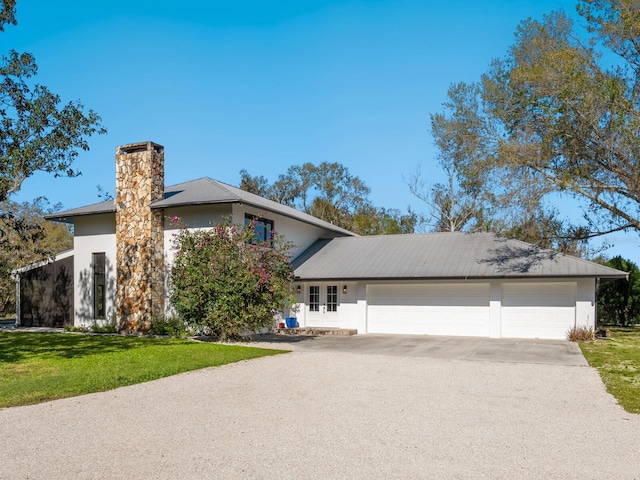 view of front of house featuring driveway, stucco siding, a chimney, an attached garage, and a front yard