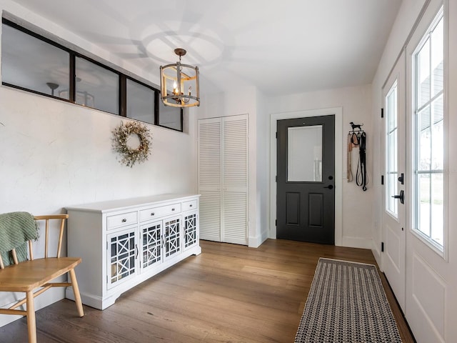 entrance foyer with a notable chandelier, baseboards, and wood finished floors