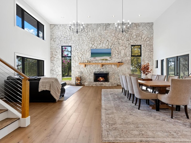 dining space featuring a high ceiling, stairway, a fireplace, and wood-type flooring