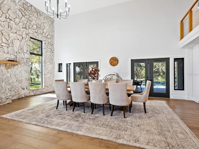 dining room with french doors, a high ceiling, hardwood / wood-style floors, and an inviting chandelier