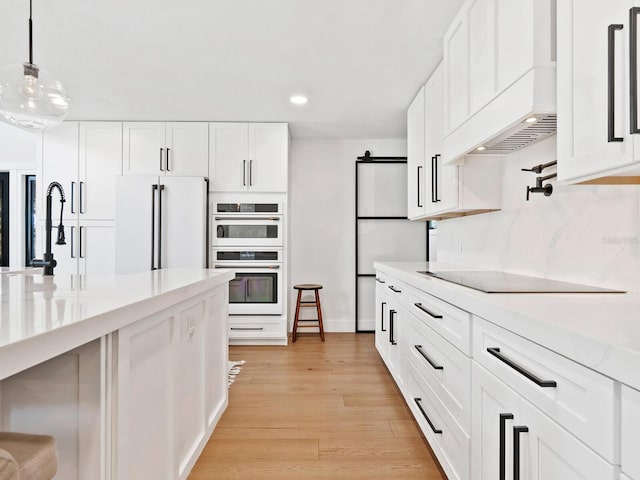 kitchen featuring white appliances, a barn door, light wood-style flooring, premium range hood, and a sink