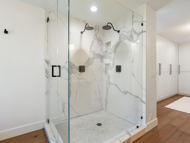 bathroom featuring wood finished floors, a marble finish shower, and baseboards