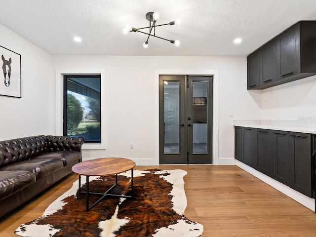 living area featuring light wood finished floors, recessed lighting, baseboards, and french doors