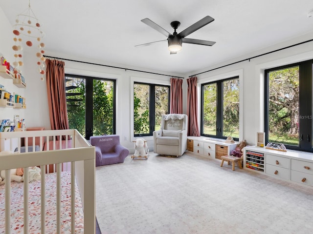 carpeted bedroom with a nursery area and ceiling fan