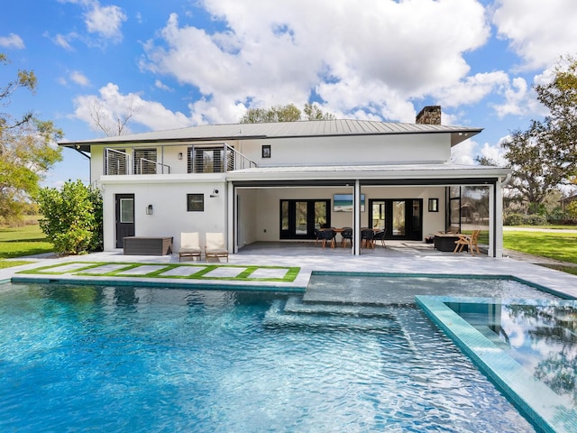 back of house featuring french doors, a chimney, a patio area, a balcony, and an outdoor pool