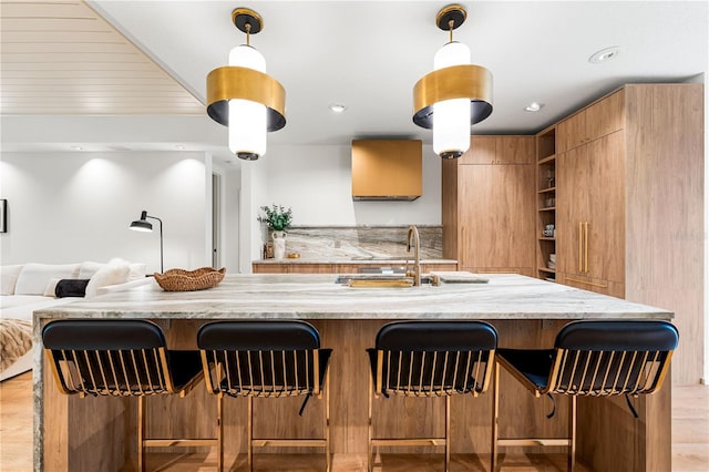 kitchen with light stone counters, a breakfast bar area, a sink, open shelves, and modern cabinets