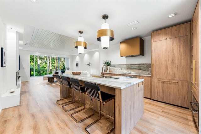 kitchen featuring a breakfast bar, hanging light fixtures, light wood-style flooring, a sink, and modern cabinets