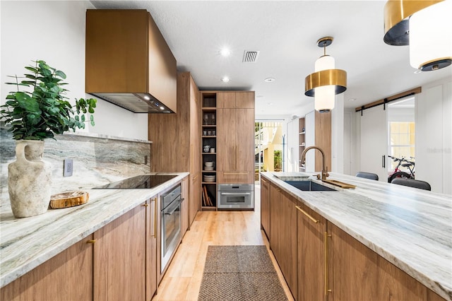 kitchen featuring black electric cooktop, stainless steel oven, custom exhaust hood, and a barn door