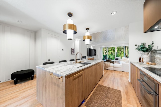 kitchen featuring light wood-style flooring, a sink, open floor plan, modern cabinets, and pendant lighting