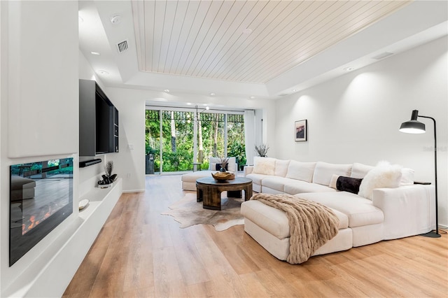 living area featuring visible vents, a tray ceiling, wooden ceiling, and light wood-style flooring