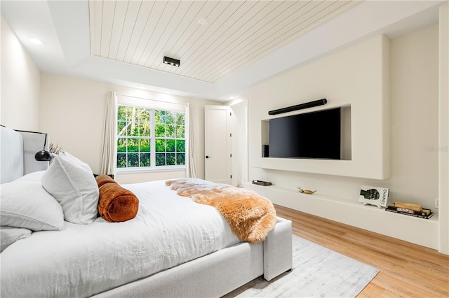 bedroom featuring a raised ceiling, wooden ceiling, and wood finished floors