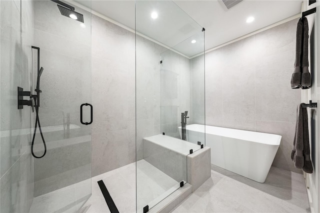 full bath featuring a freestanding tub, recessed lighting, visible vents, tile walls, and a shower stall