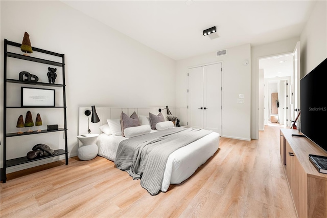 bedroom featuring light wood finished floors, a closet, visible vents, and baseboards