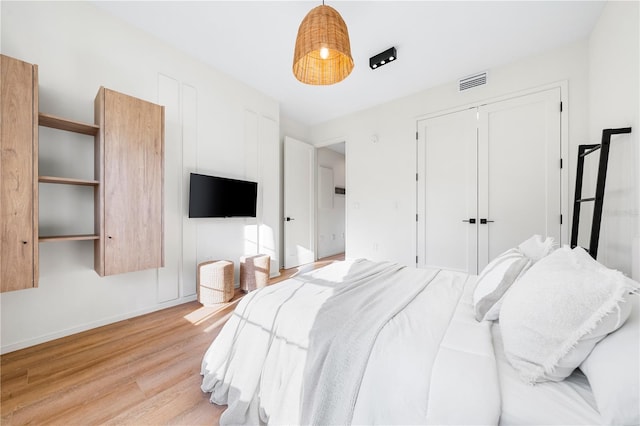 bedroom with a closet, visible vents, baseboards, and light wood finished floors