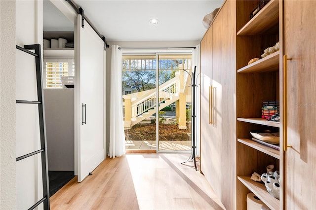 doorway with light wood finished floors and a barn door