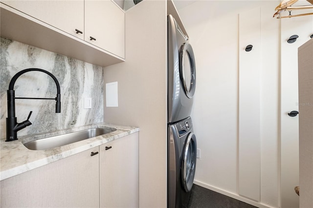 clothes washing area with stacked washer / dryer, cabinet space, and a sink