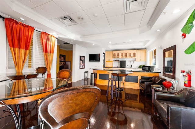 interior space featuring dark wood-style floors, ornamental molding, a raised ceiling, and visible vents