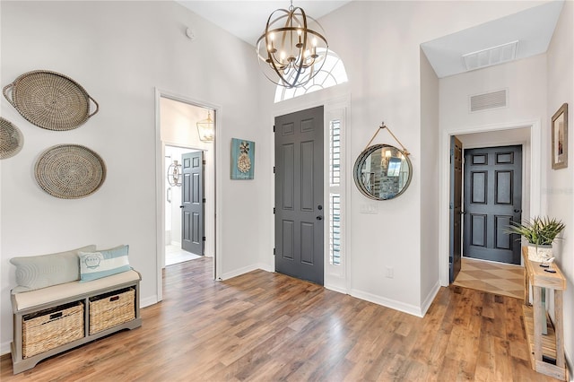 foyer entrance with visible vents, light wood-style flooring, and an inviting chandelier