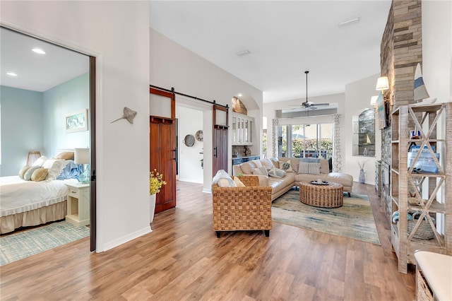 living room with a barn door, baseboards, ceiling fan, light wood-style flooring, and recessed lighting