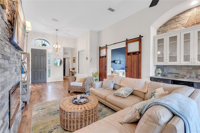 living room featuring visible vents, a notable chandelier, light wood-style flooring, and a barn door