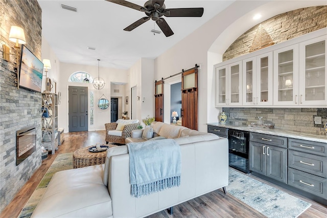 living area with a ceiling fan, wood finished floors, visible vents, and a barn door