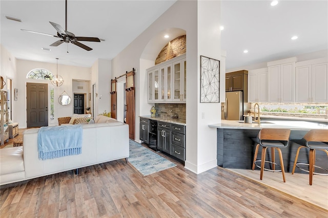 kitchen with visible vents, a breakfast bar, open floor plan, stainless steel refrigerator with ice dispenser, and backsplash