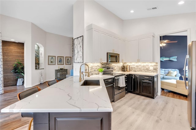 kitchen with visible vents, decorative backsplash, light stone counters, stainless steel appliances, and white cabinetry