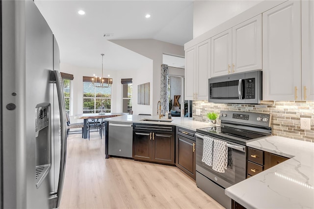 kitchen with a peninsula, backsplash, stainless steel appliances, and a sink