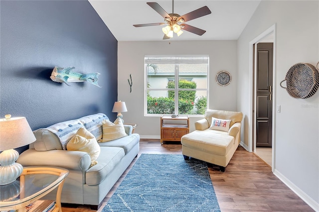 living room featuring lofted ceiling, baseboards, and wood finished floors