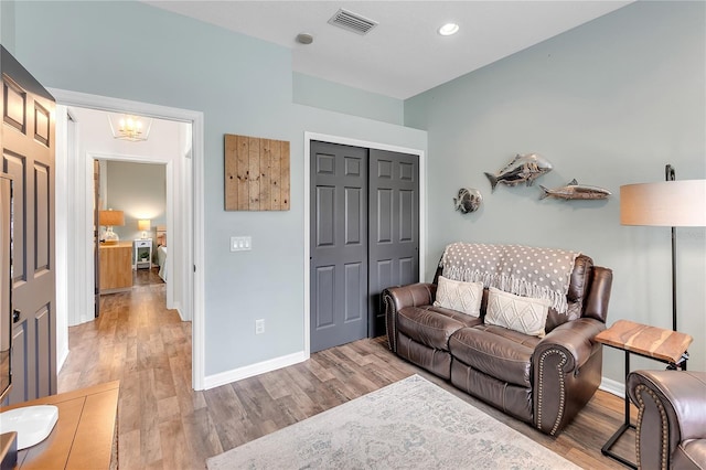 living area with visible vents, a notable chandelier, baseboards, and wood finished floors