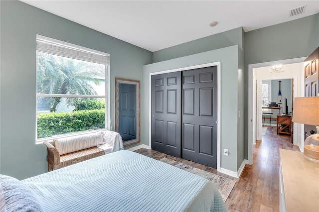 bedroom featuring a notable chandelier, a closet, visible vents, light wood-style floors, and baseboards