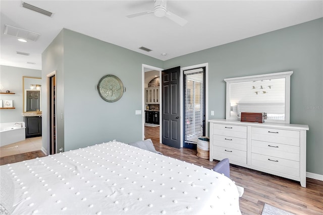 bedroom featuring a ceiling fan, visible vents, ensuite bath, and wood finished floors