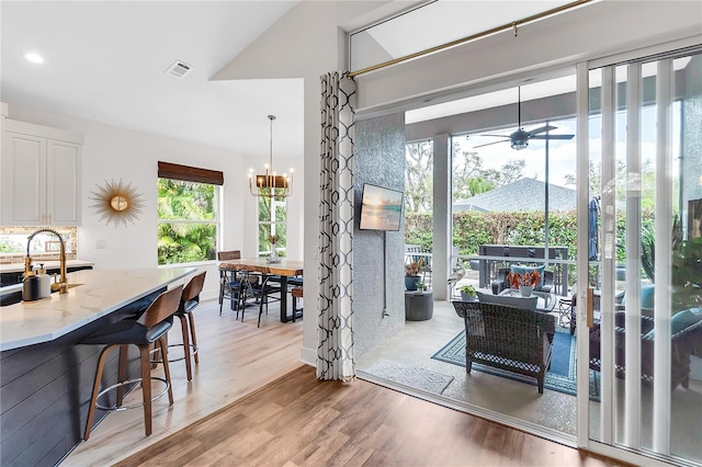 dining area with ceiling fan with notable chandelier, light wood-style flooring, and visible vents