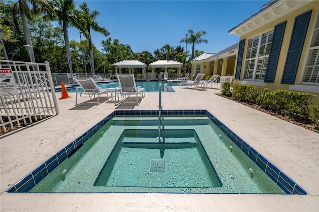 pool with a hot tub, fence, and a patio