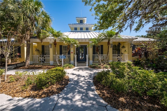 view of front of home with covered porch, stucco siding, metal roof, and a standing seam roof