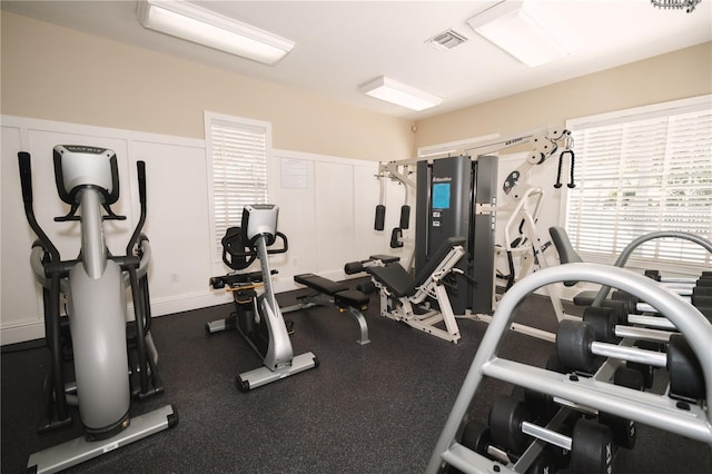 exercise room with a wainscoted wall, visible vents, and a decorative wall