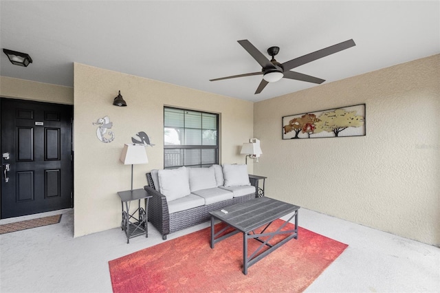 carpeted living area featuring ceiling fan and a textured wall