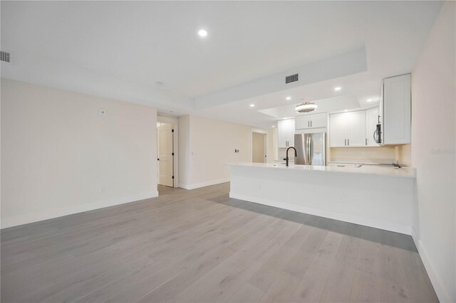 unfurnished living room featuring visible vents, light wood finished floors, baseboards, recessed lighting, and a sink