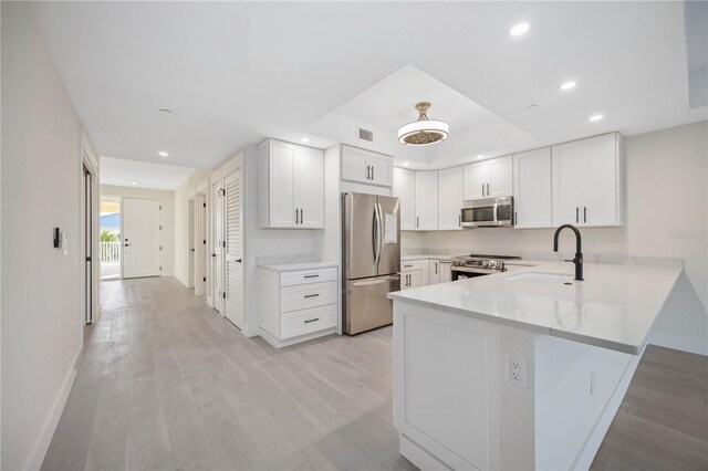 kitchen with visible vents, a peninsula, a sink, stainless steel appliances, and light countertops